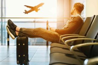 A man sitting on a bench watching a plane take off